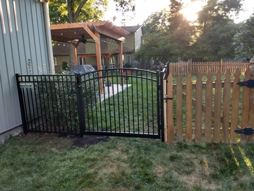 Garden with black metal and wooden fence.