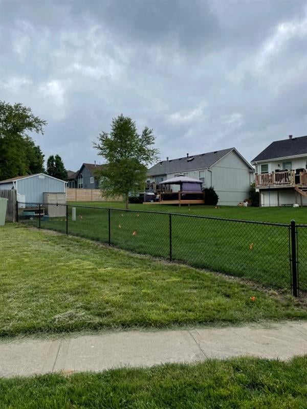 Suburban homes with a green lawn and a black metal fence.