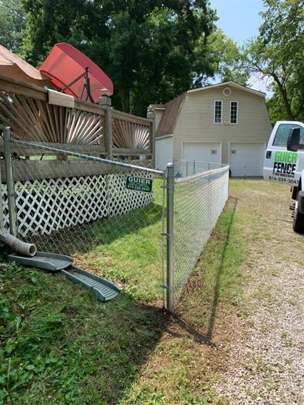 A clear glass or acrylic panel leaning against a white fence on a sunny day.