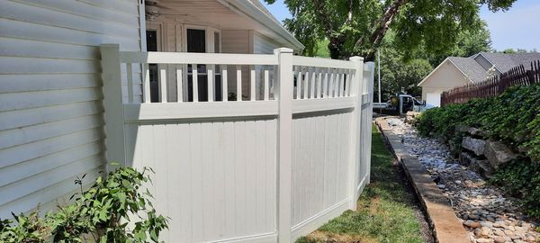 White vinyl privacy fence with vertical slats on top.