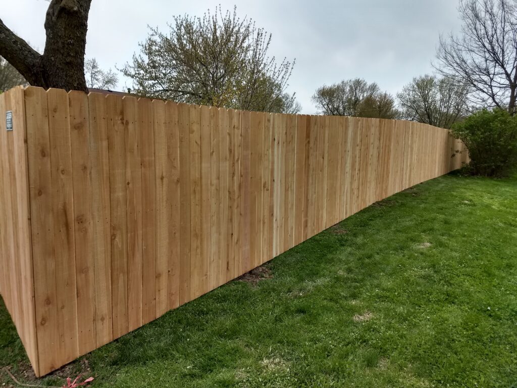 A newly installed wooden fence on a grassy slope under a cloudy sky.