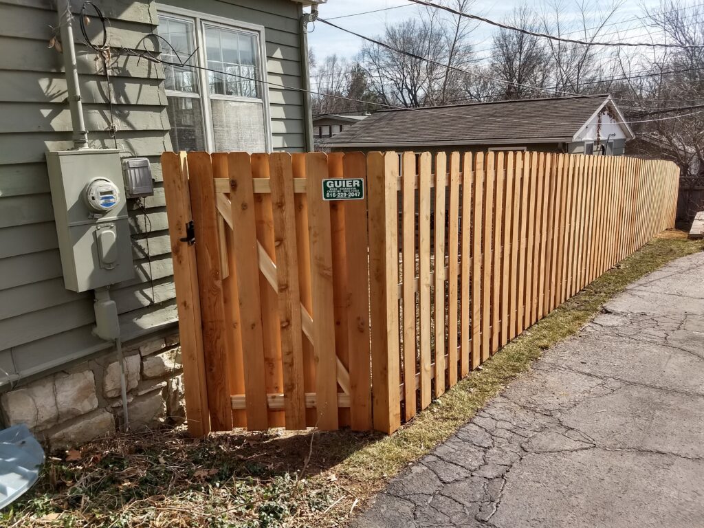A wooden fence with a gate next to a house.