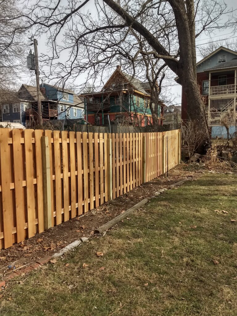New wooden fence dividing two yards in a suburban neighborhood.