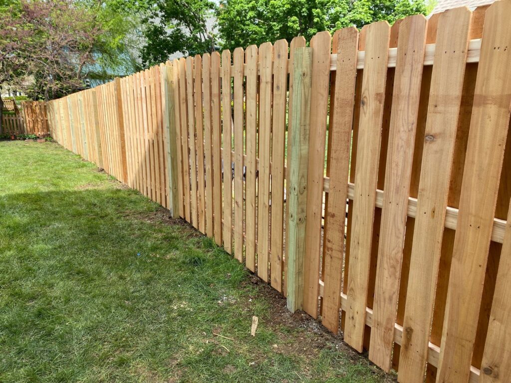 Wooden fence bordering grass.