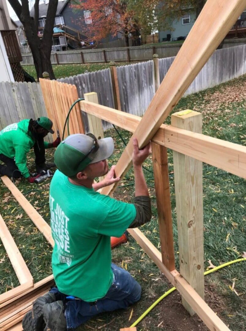 Workers repair wooden fence.
